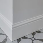 parede branca com um rodapé branco e chão preto e branco