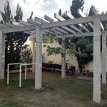 Pergolado de concreto em um jardim.